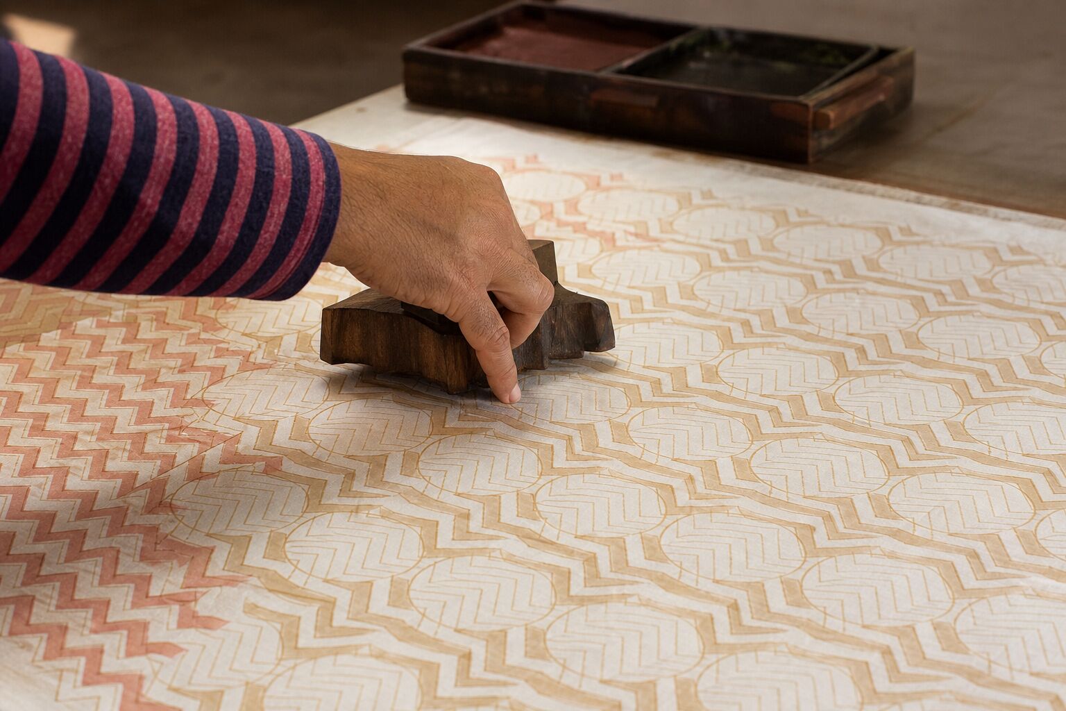 Hand block printed cotton fabric with layered floral motifs in warm natural light