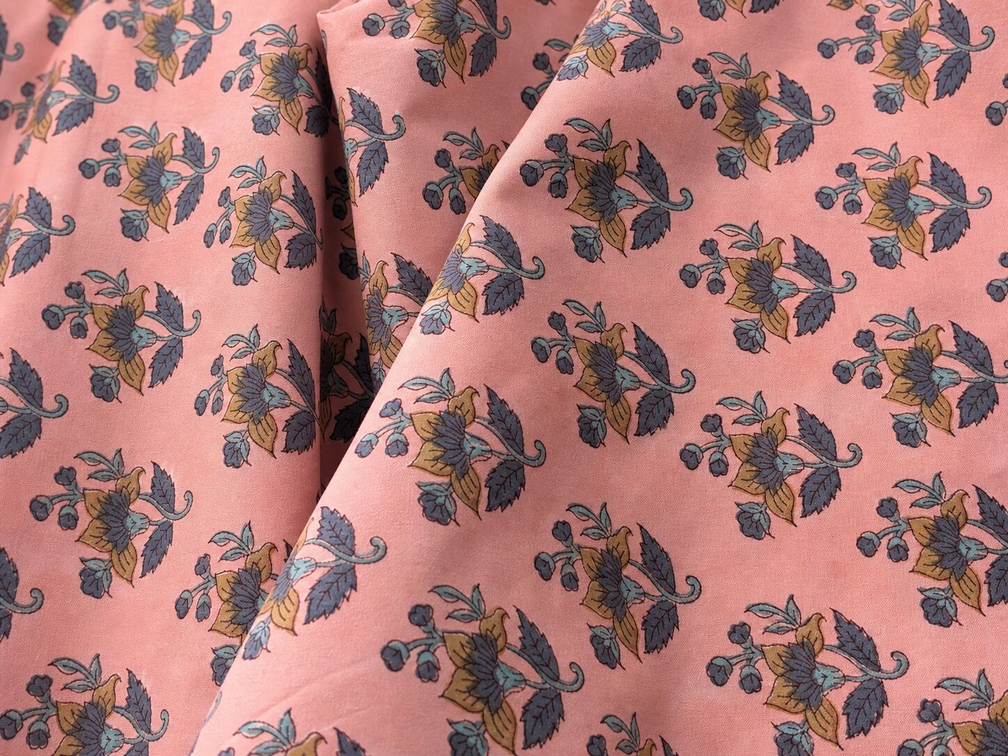 Close-up of pink hand block printed cotton fabric with visible weave and soft drape