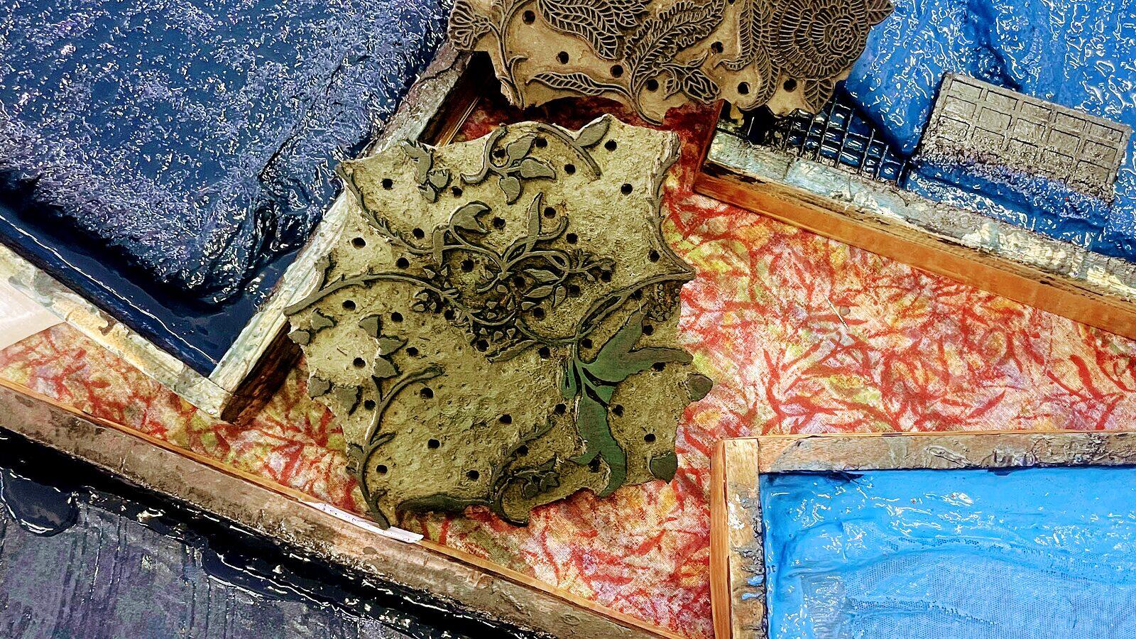 Carved wooden printing blocks resting on trays of blue and red dye at a Jaipur workshop