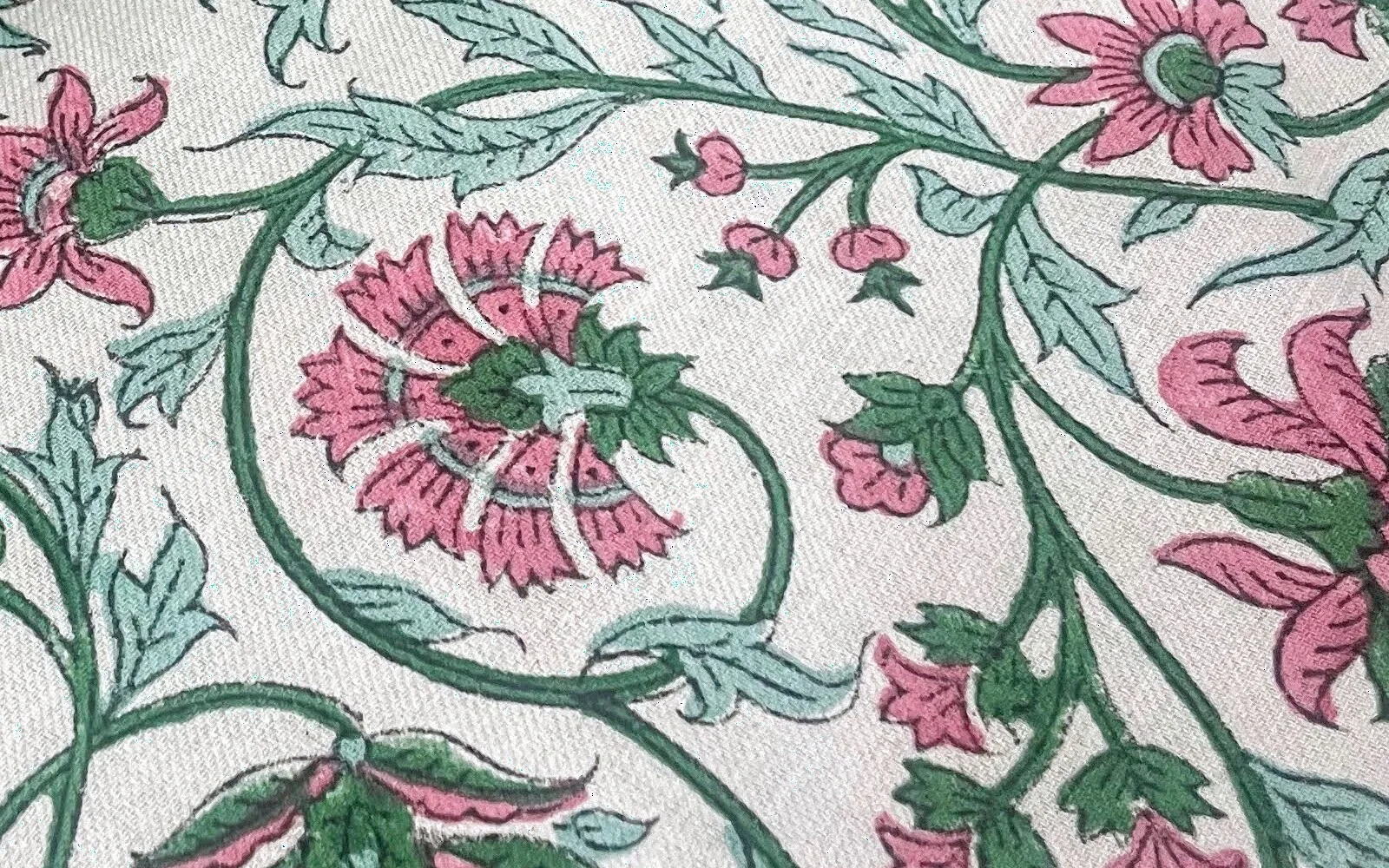 Close view of fine lines within pink flowers and green leaves on the printed cloth